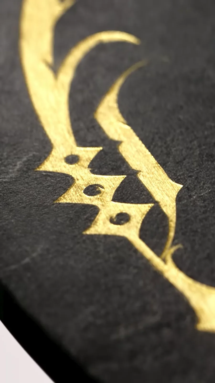 Trazo caligráfico en oro grabado sobre la base de piedra de la mesa Rubica